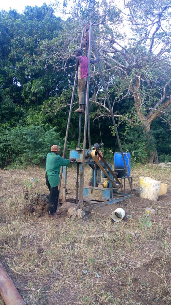Workers drilling for water by hand on a rural site